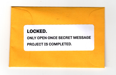 Scan of closed yellow packet: 'LOCKED. ONLY OPEN ONCE SECRET MESSAGE PROJECT IS COMPLETED'