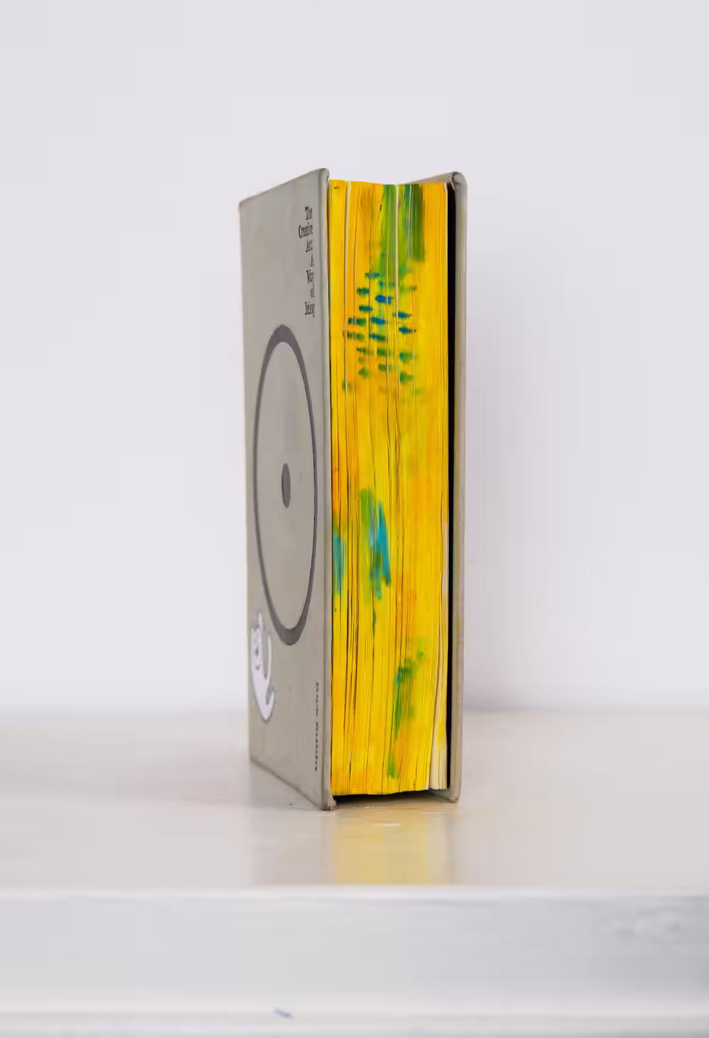 Side view photo of The Creative Act: A Way of Being, showing off the brightly painted yellow/blue fore-edge.